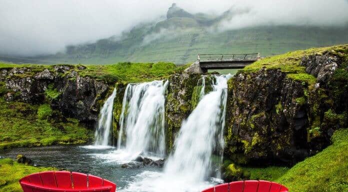 Two red chairs overlooking a waterfall in Iceland during summer season