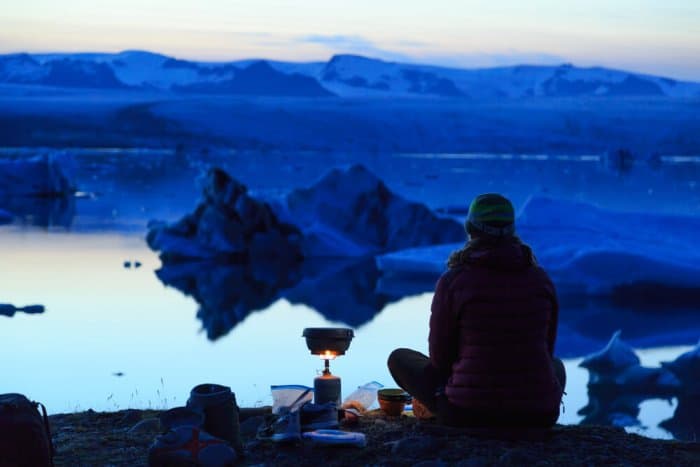 Woman cooking on her rental gas stove while camping in Iceland