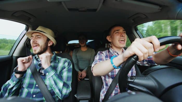 Friends in a car singing along to their road trip playlist