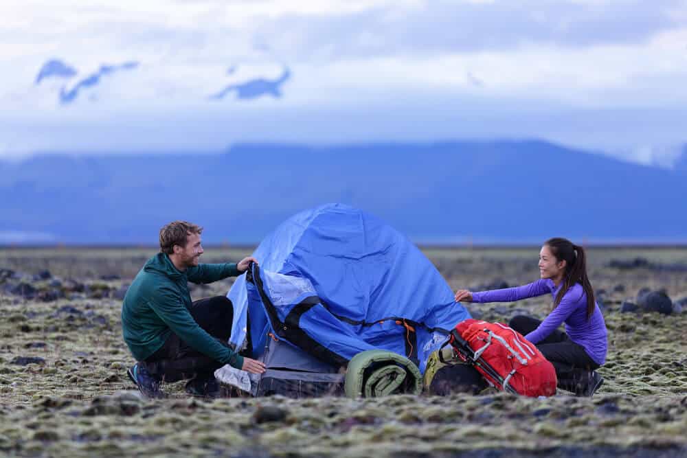 Couple setting a tent, a cheap option if camping on a budget
