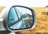 Mountains and road in car rearview mirror in Iceland with times and distances