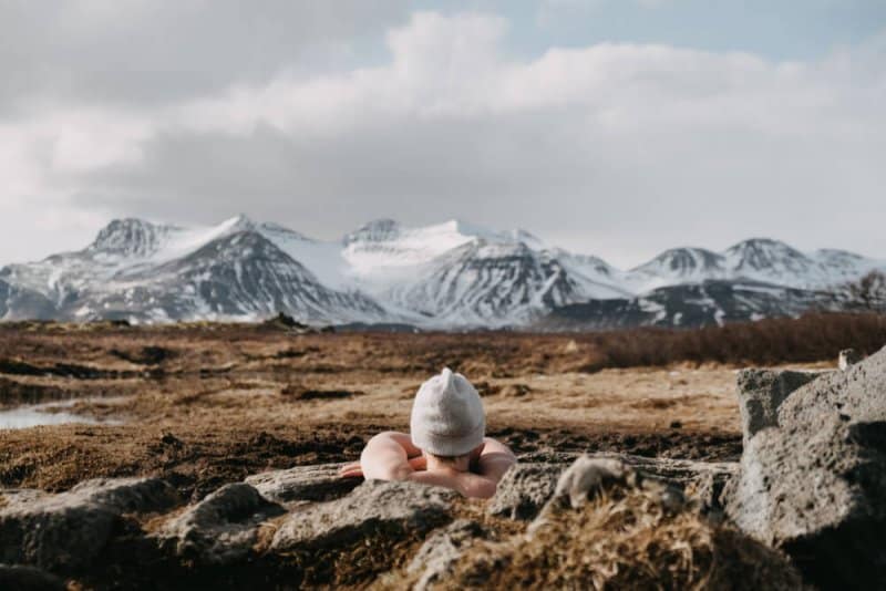 Tourist relaxing in a hot pot in Iceland admiring winter scenery