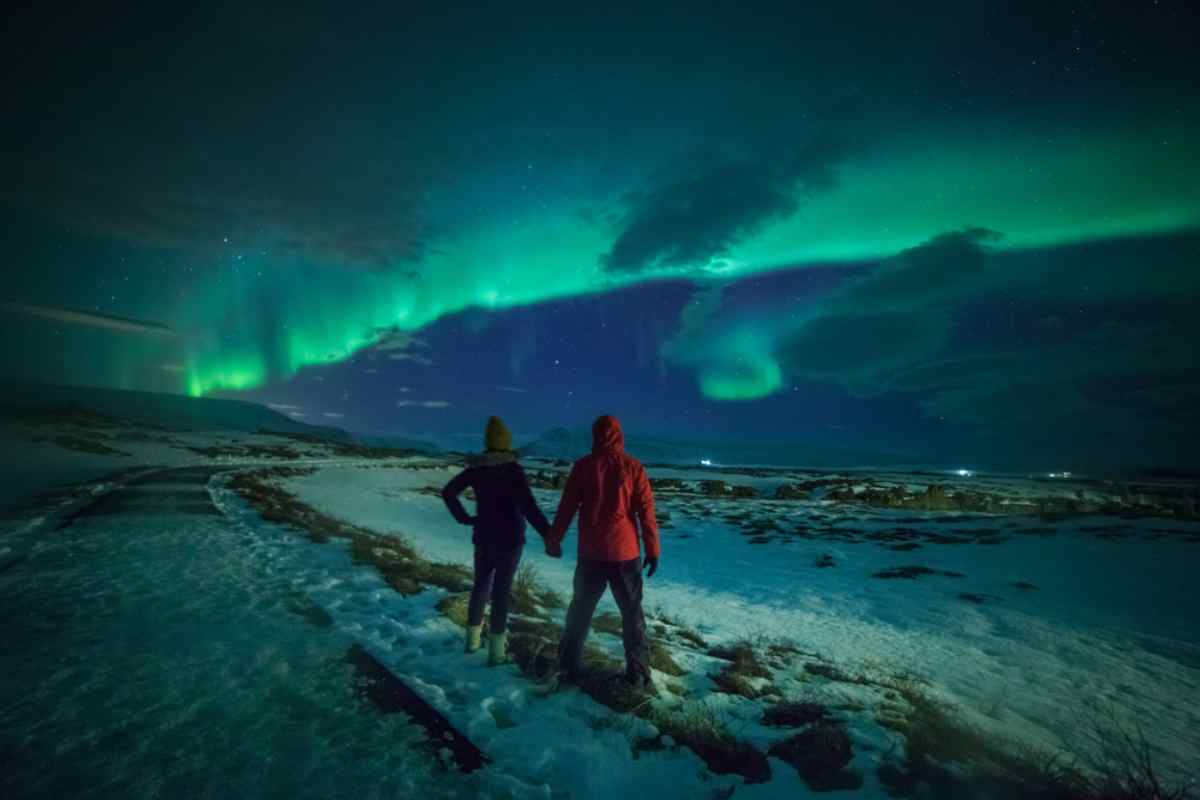 Couple enjoying the northern lights dancing in the sky