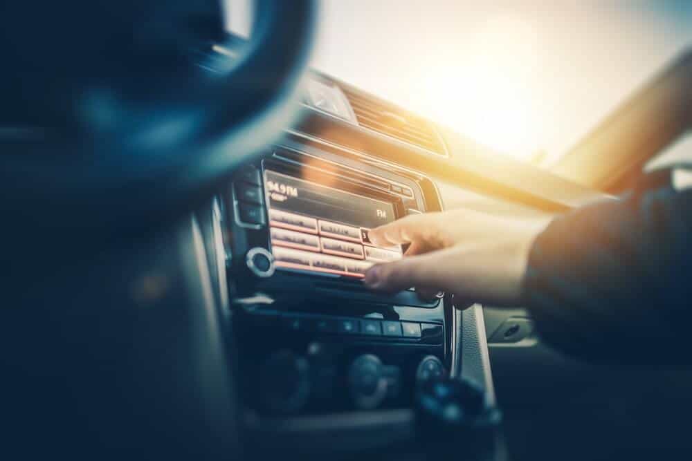 Man changing the dial on the radio to find a good road trip car song