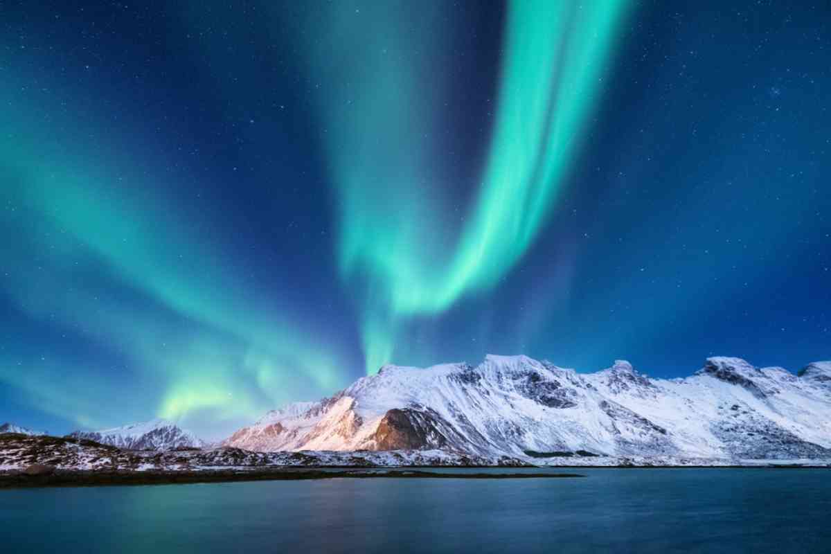 Northern lights over a snow-covered mountain of a fjord