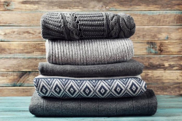 Pile of winter sweaters to pack for suitcase for Iceland trip
