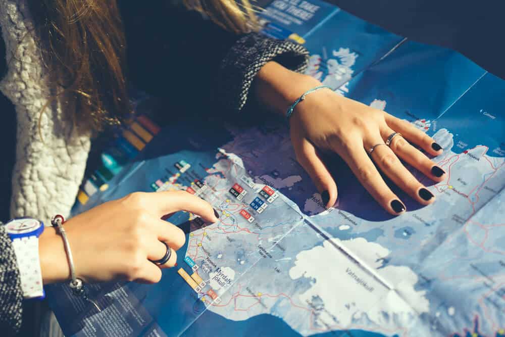 girl checking her itinerary on her road trip map of Iceland