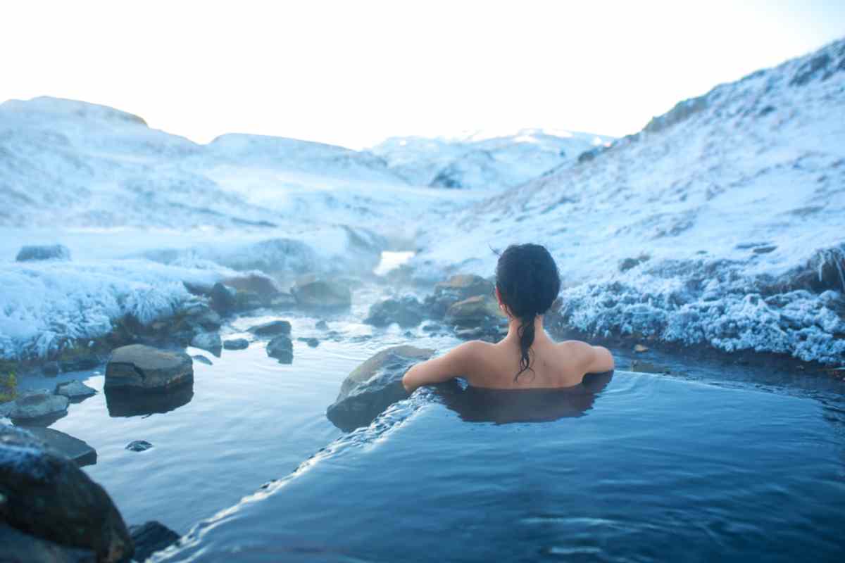 Woman enjoying a hot spring in December surrounded by snow