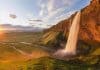 Midnight sun in Iceland on the horizon with a waterfall